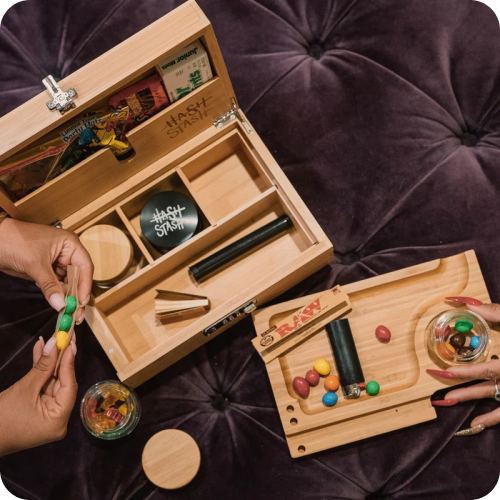 People handling colorful items near a wooden stash box on a purple surface.